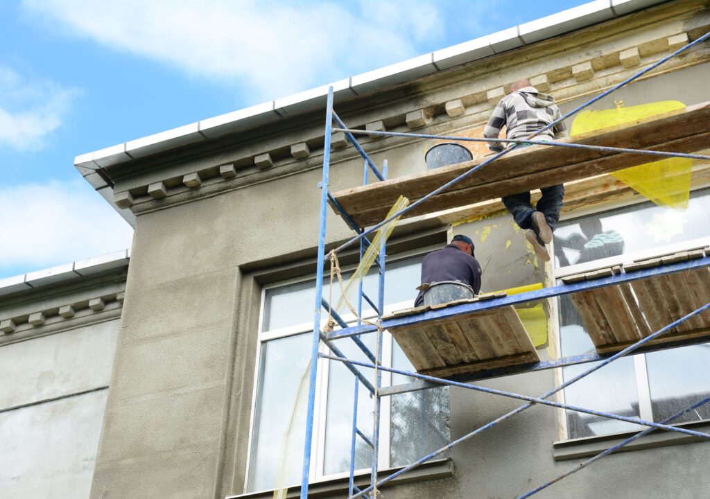 Ouvrier façadier rénovant le mur extérieur d'une maison.